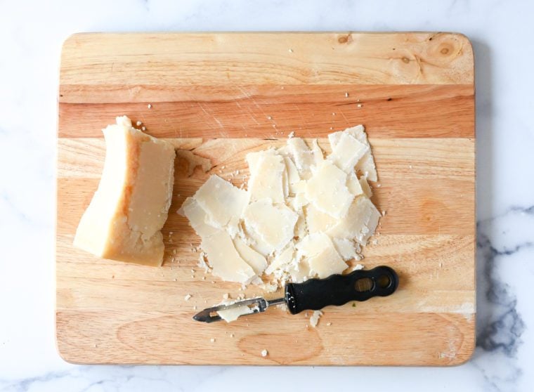 shaving parmigiano reggiano on cutting board