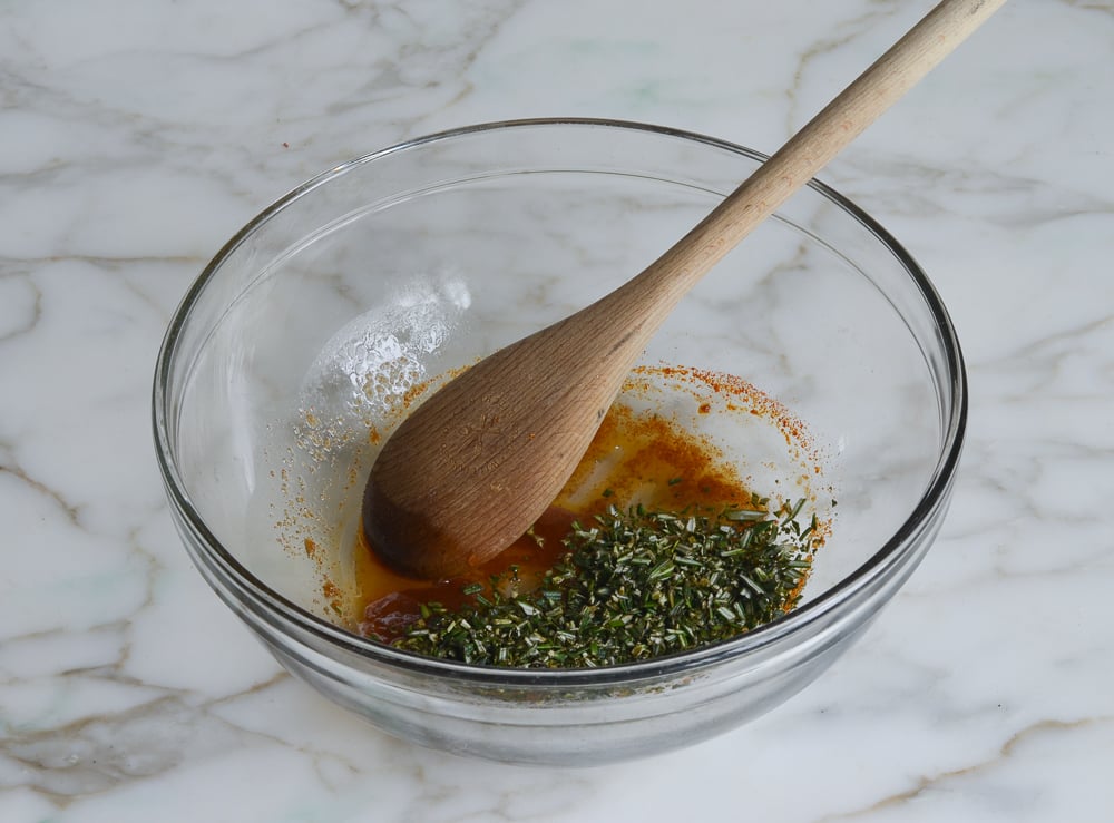 Small bowl with rosemary, butter, cayenne, and brown sugar.