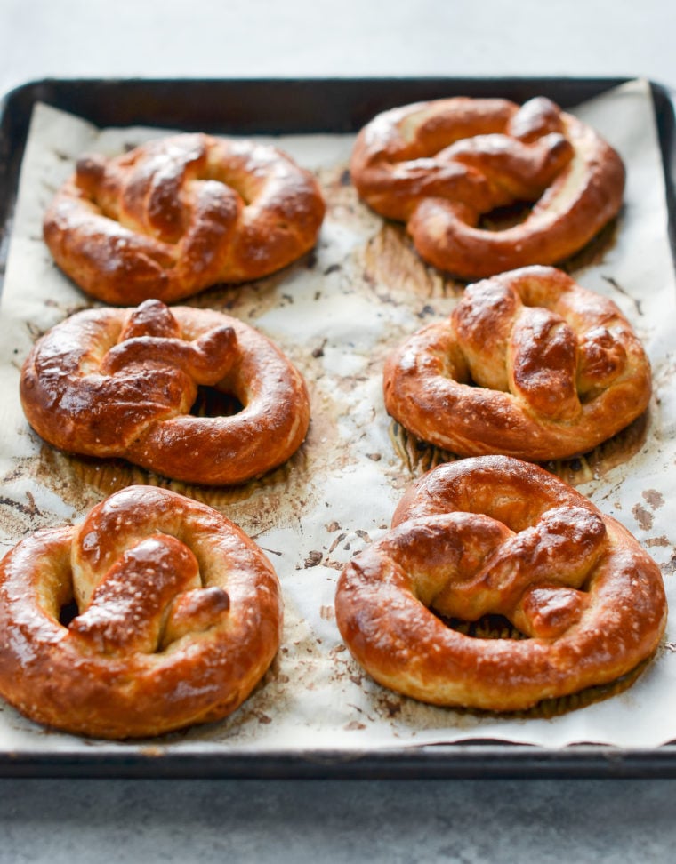 Soft pretzels on a lined baking sheet.