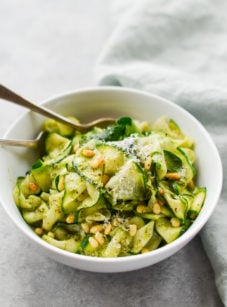 Bowl of zucchini noodles with pesto and pine nuts.