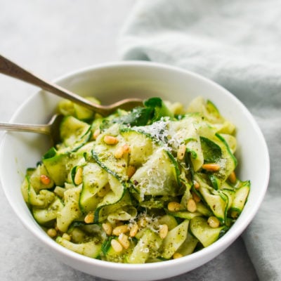 Bowl of zucchini noodles with pesto and pine nuts.
