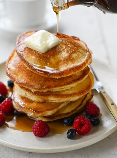 Syrup drizzling onto a stack of pancakes.