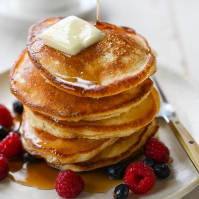 Syrup drizzling onto a stack of pancakes.