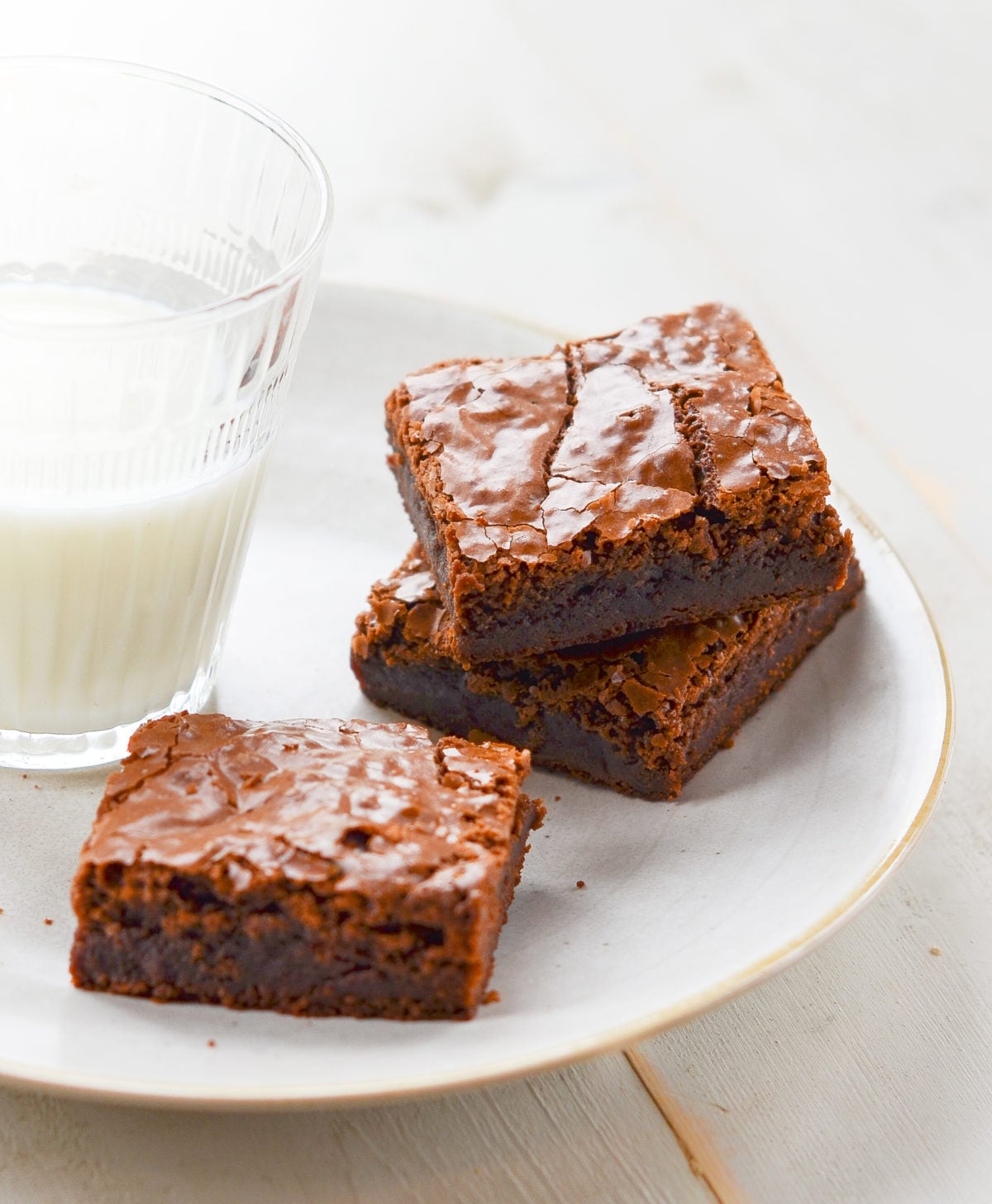 Brownies on a plate with a glass of milk.