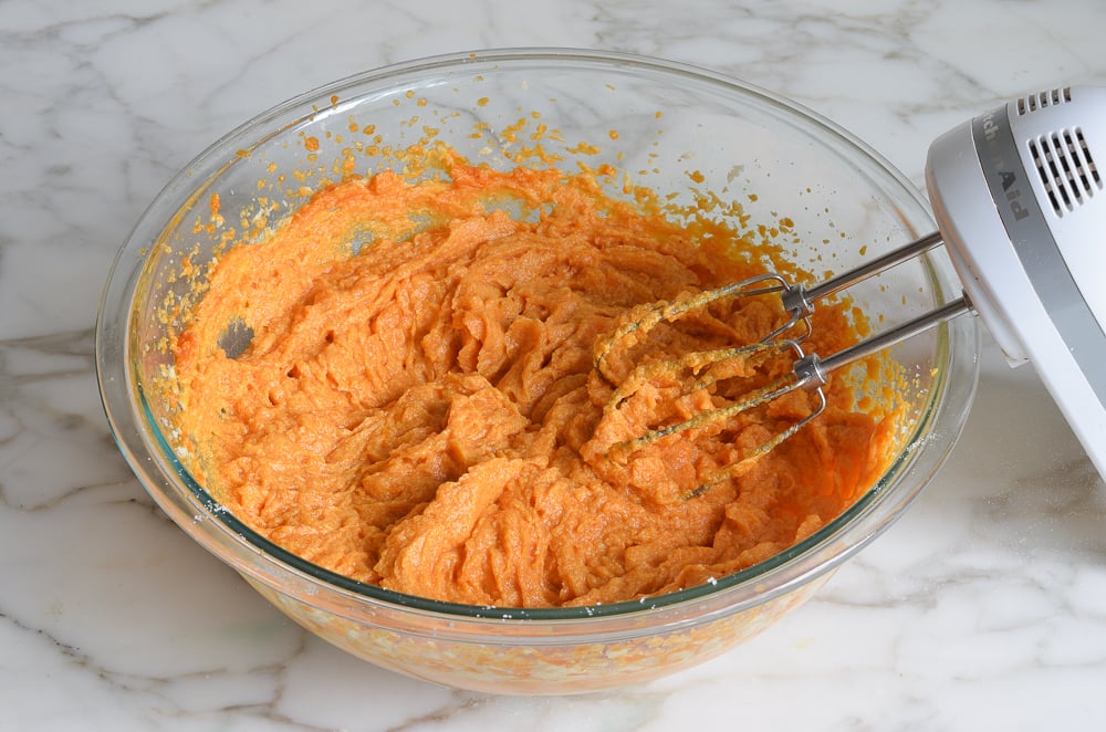 Electric mixer with a light orange-colored mixture.