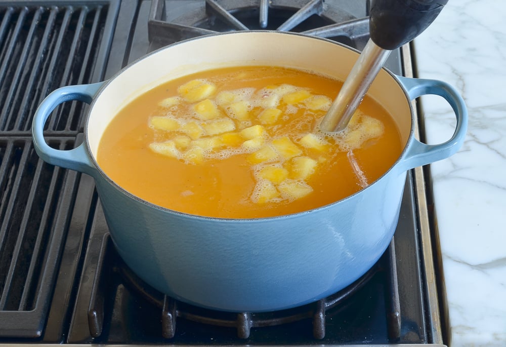 Immersion blender in a Dutch oven of soup.
