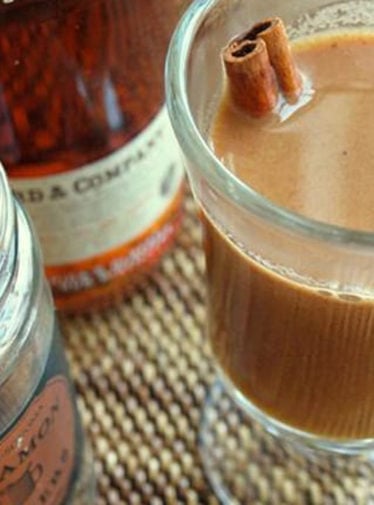Cinnamon stick in a glass of hot buttered apple cider with rum.