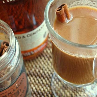 Cinnamon stick in a glass of hot buttered apple cider with rum.