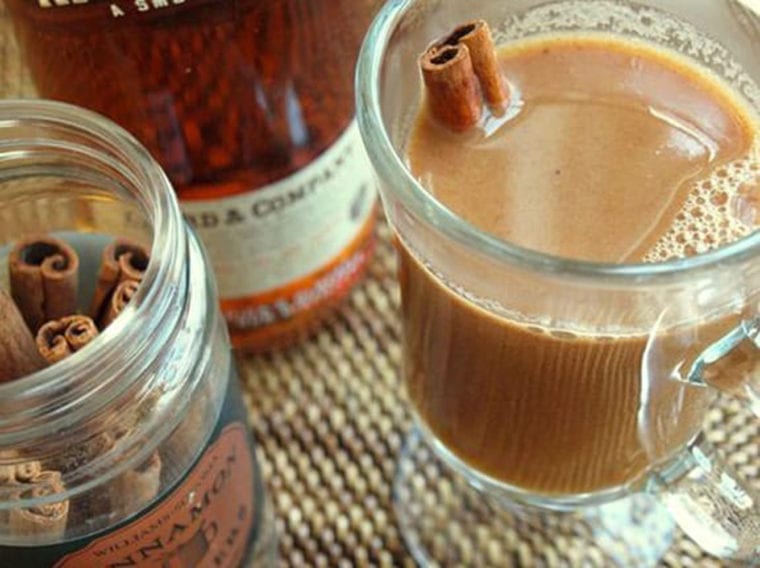 Cinnamon stick in a glass of hot buttered apple cider with rum.