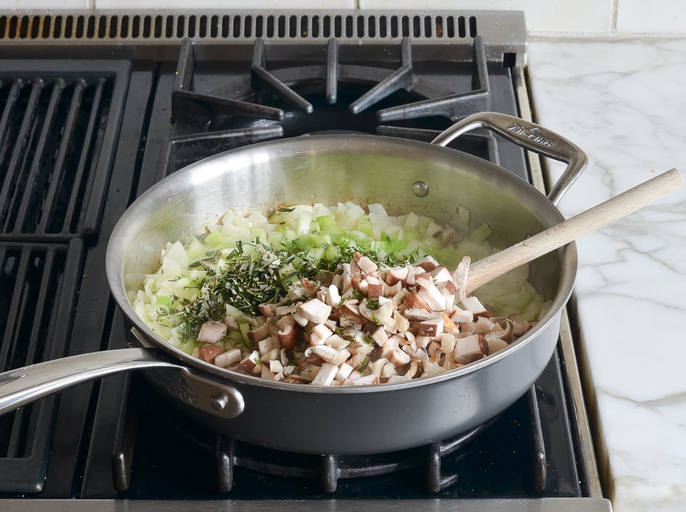 Mushrooms, herbs, and other ingredients in a skillet.