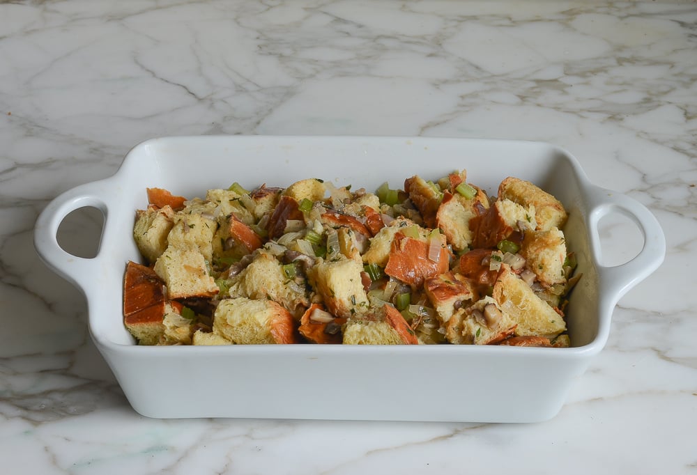 Uncooked challah, wild mushroom, and herb stuffing in a baking dish.