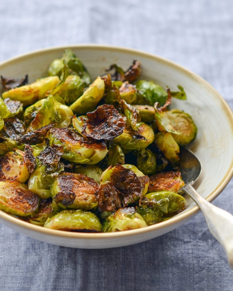 Spoon in a bowl of roasted brussels sprouts.