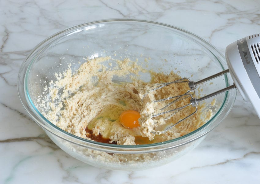Eggs and vanilla in a bowl with creamed butter and sugar.