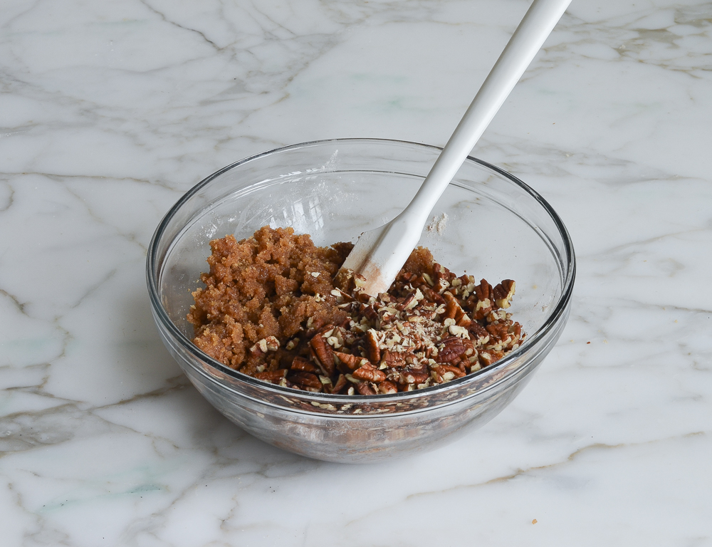Chopped nuts in a bowl with a brown sugar mixture.