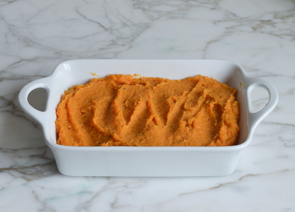 Casserole dish full of mashed sweet potato mixture.