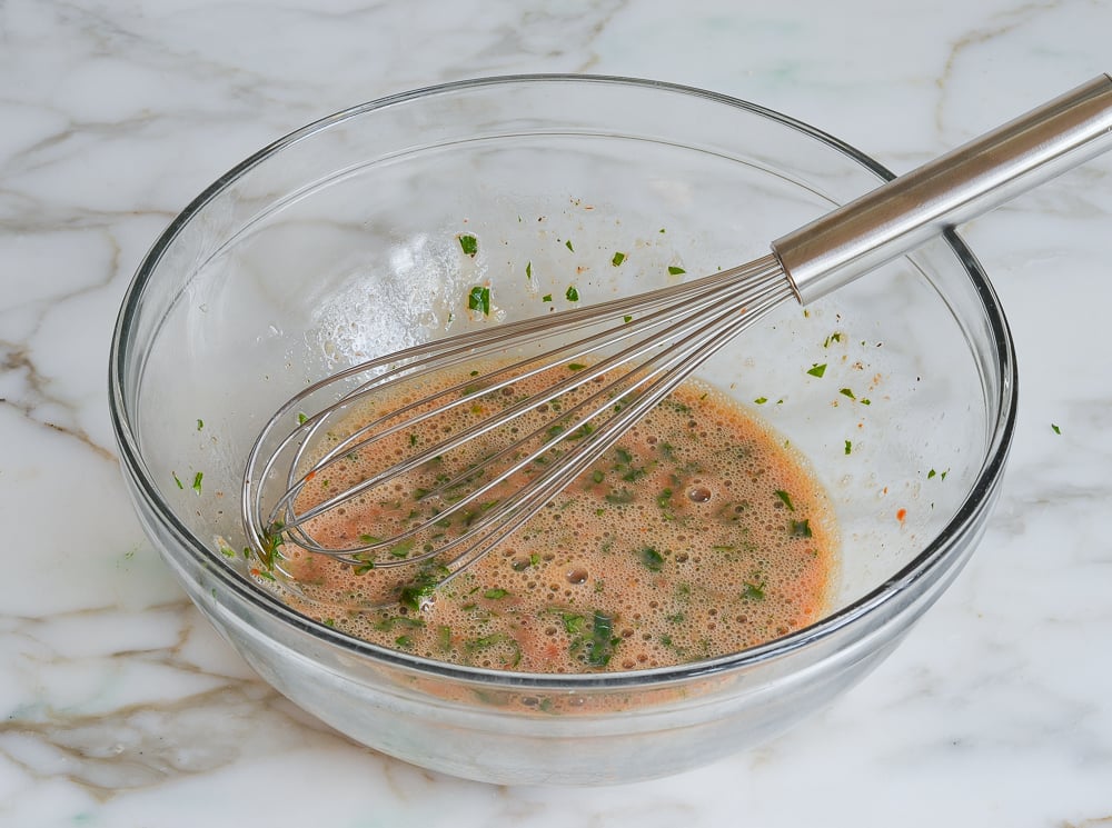 Whisk in a bowl of ingredients for meatballs.