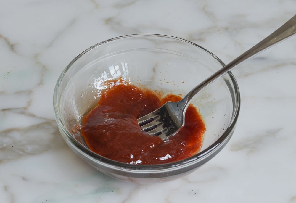 Fork in a bowl of tomato-balsamic glaze.