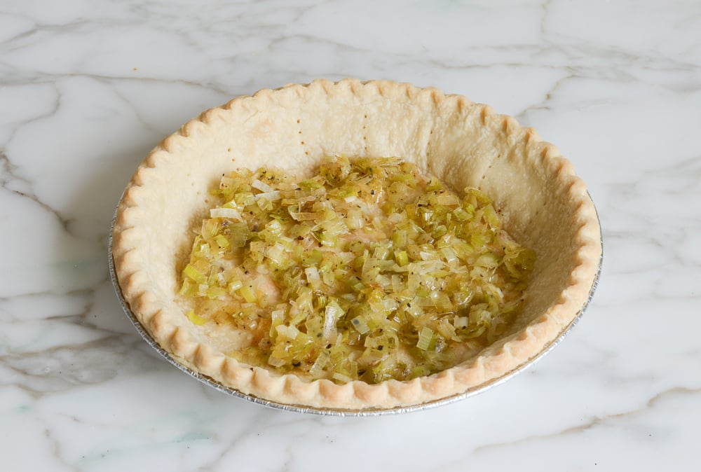 spreading cooked leeks over crust