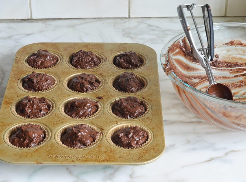 Muffin pan full of chocolate muffin batter.