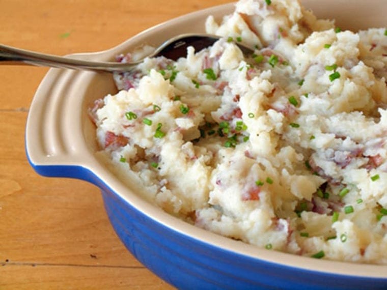 Spoon in a dish of parmesan smashed potatoes.