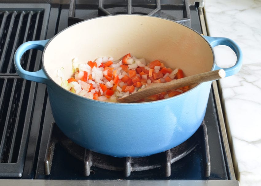 Onions and red peppers in a Dutch oven.