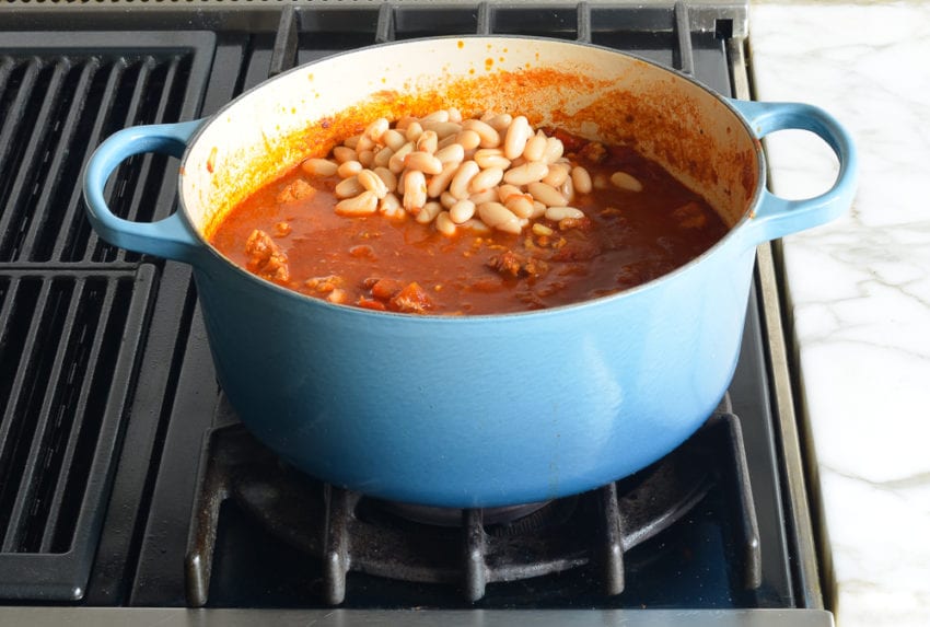 White beans in a pot of tomato and chicken mixture.