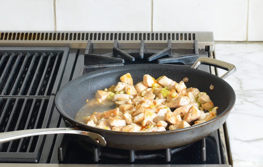 Chicken in a skillet with seasonings.