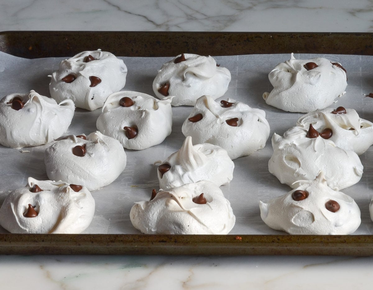baked chocolate chip meringue cookies cooling on baking sheet