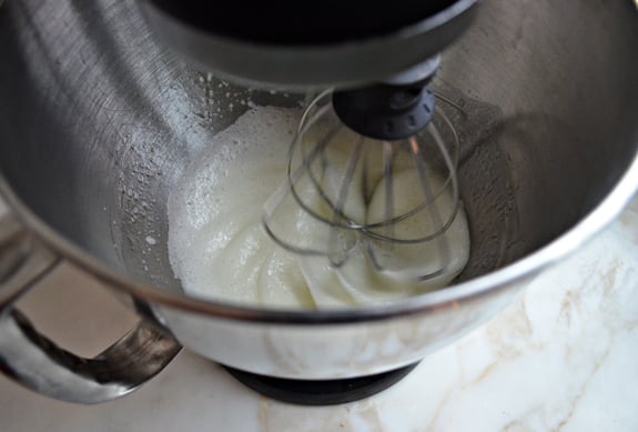 Stand mixer whisking eggs that are creamy white.