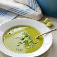 Spoon in a bowl of pea soup with basil.
