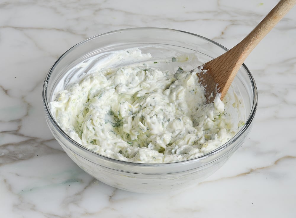 Wooden spoon mixing tzatziki.