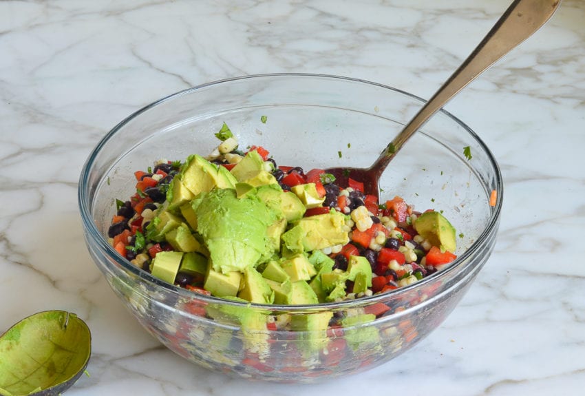 adding diced avocado to black bean salad