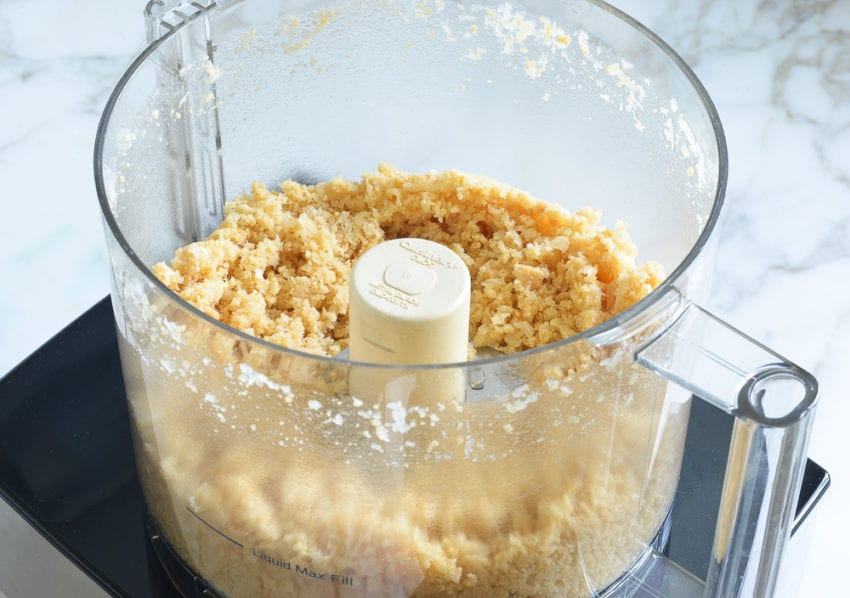 Crumbled pie crust ingredients in a food processor.