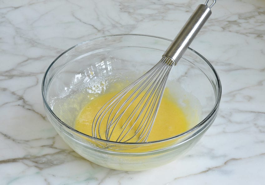 Whisk in a bowl with an egg mixture.