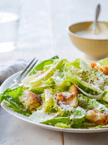 Fork on a plate with a Caesar salad.