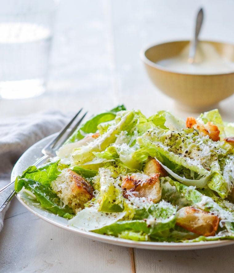 Fork on a plate with a Caesar salad.