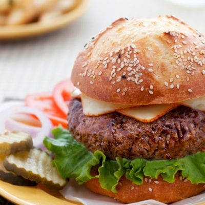 Steakhouse burger on a plate with burger toppings.