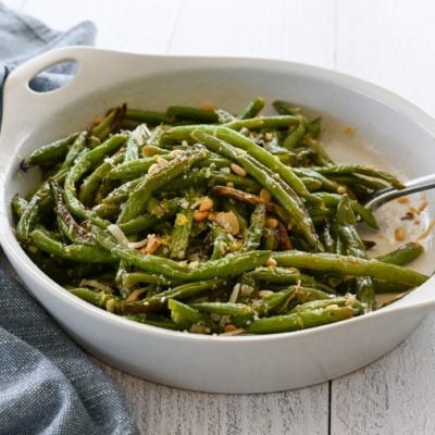 Dish of roasted green beans with garlic, lemon, pine nuts, and parmesan.