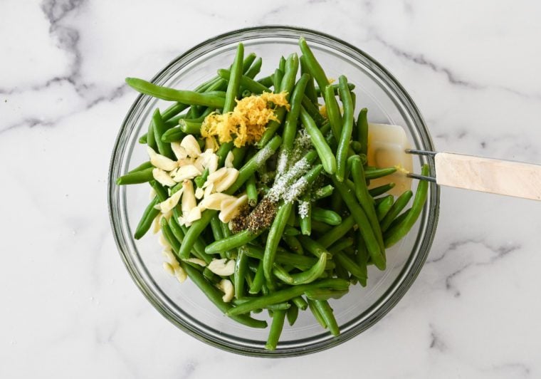 green beans, olive oil, lemon zest, garlic, salt, pepper, and sugar in bowl