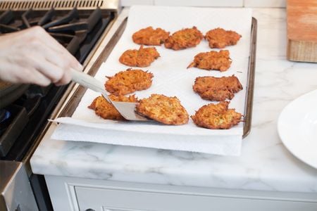 SweetPotatoPancakes 3 Spatula grabbing a curried sweet potato pancake from a lined baking sheet.