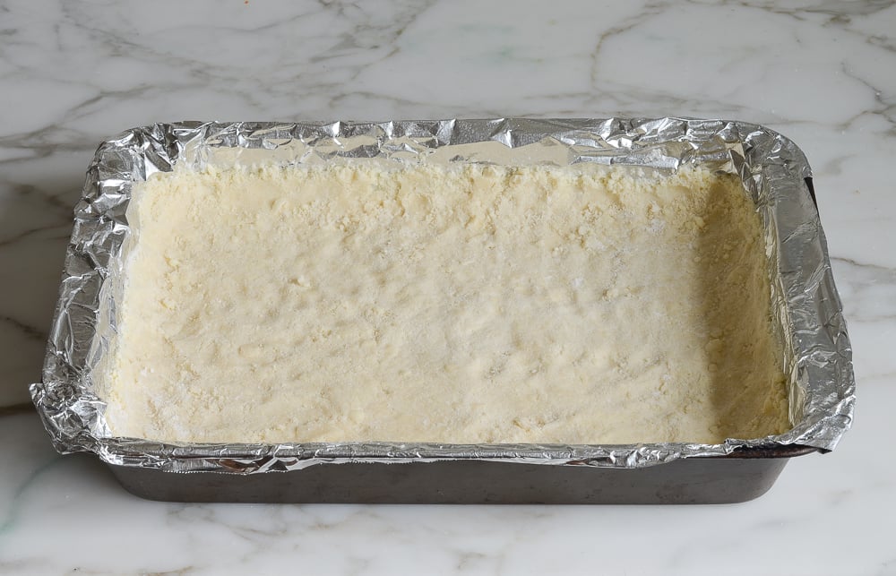 Pressing mixture into pan to make the lemon squares crust.