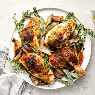 roast chicken on platter with sauce on side.