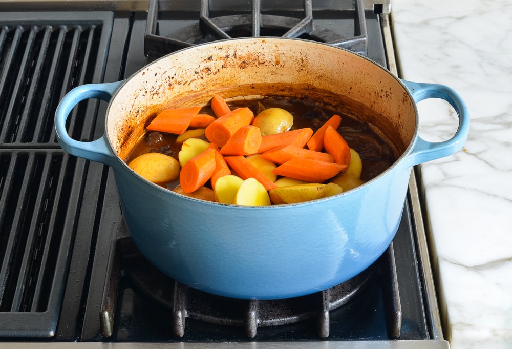 Carrots and potatoes in a Dutch oven with broth.