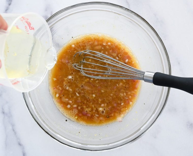 adding oil to whisked vinegar mixture