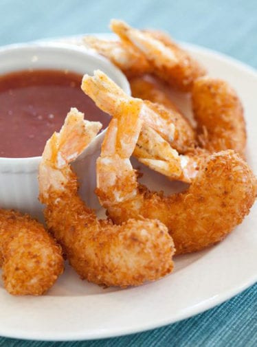 White plate of coconut shrimp with dip.
