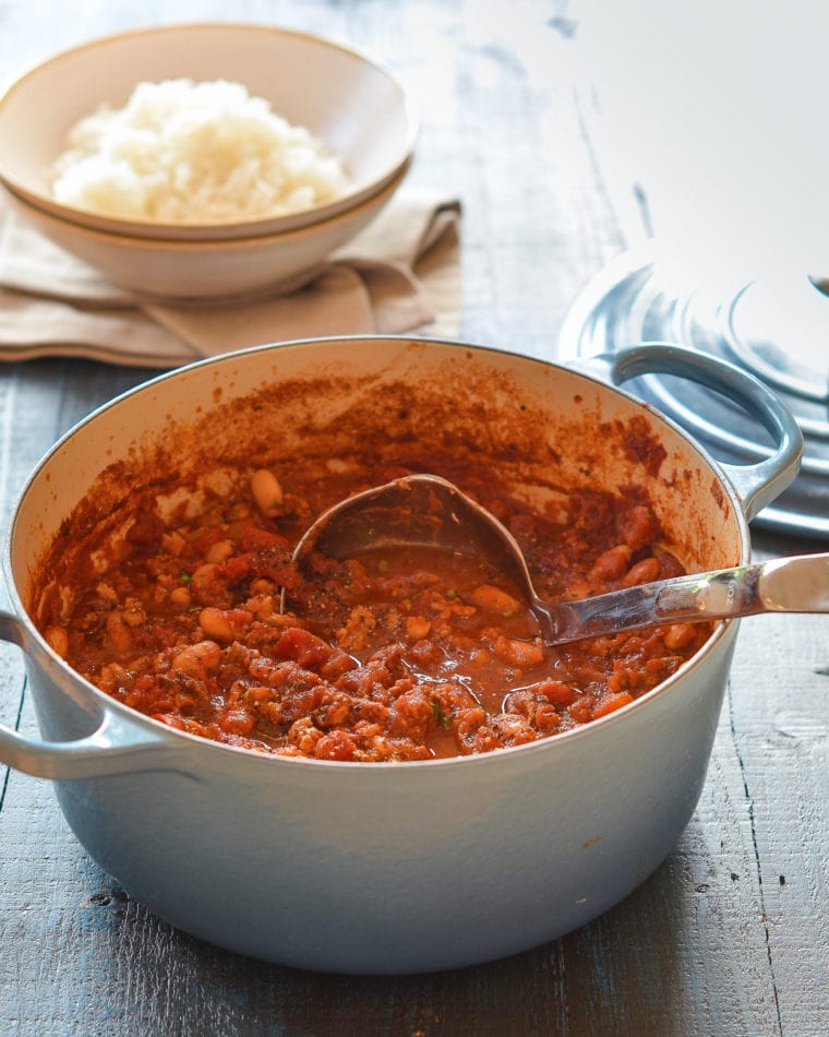 Ladle in a Dutch oven of chicken chili.