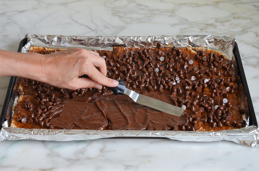 spreading chocolate chips over toffee