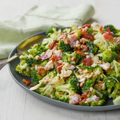 Spoon on a plate of broccoli salad with bacon, cheddar, and almonds.