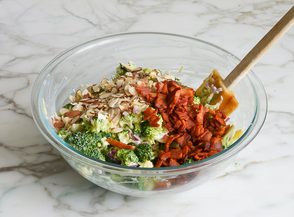 adding the bacon and almonds to broccoli salad