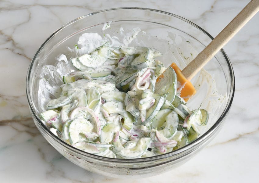 Vegetables tossed in a bowl with white dressing.